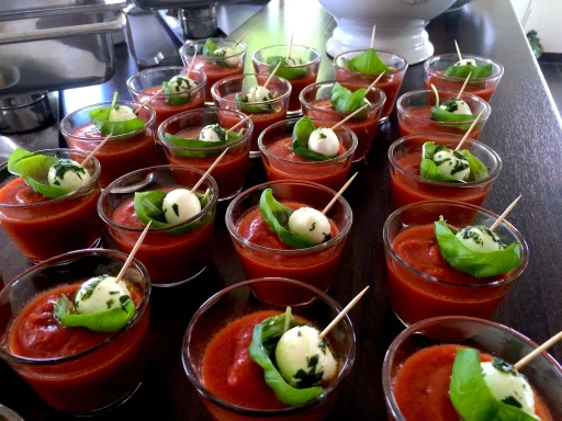 Mediterrane Vorspeise im Glas Tomatensuppe in Gläsern mit Mozzarella-Kugeln und Basilikum.
