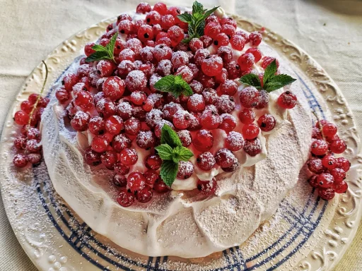 Beerentorte mit roten Johannisbeeren Torte mit einer dekorativen Schicht aus roten Beeren und frischen Minzblättern.